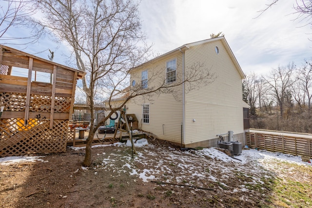 snow covered rear of property featuring a deck and fence