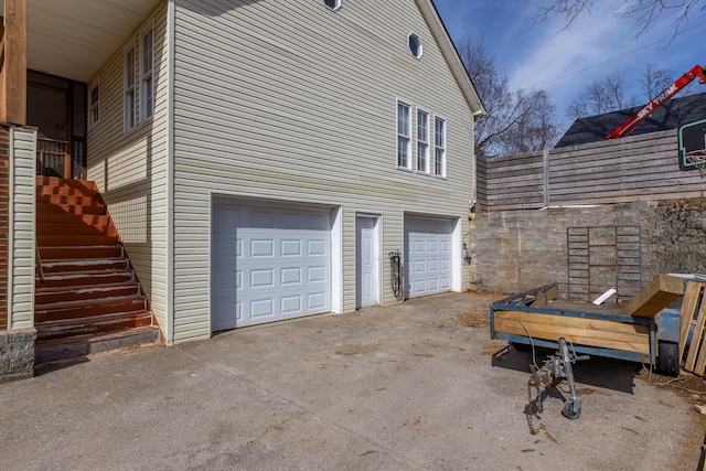 view of side of property featuring a garage, driveway, and stairway