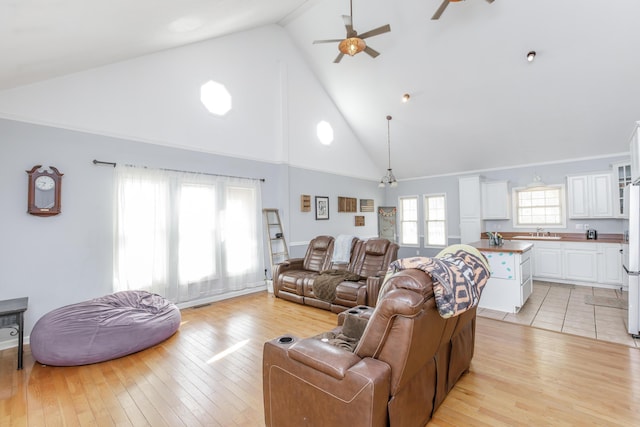 living area featuring high vaulted ceiling, light wood-type flooring, and ceiling fan