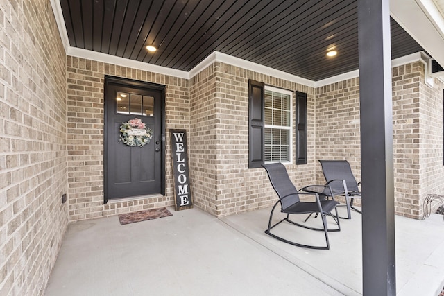 entrance to property with covered porch and brick siding