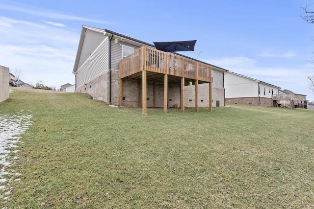 rear view of property with brick siding, a yard, and a deck