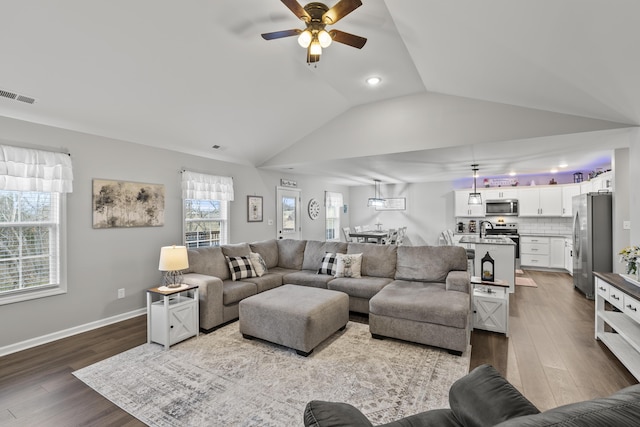 living room featuring vaulted ceiling, baseboards, visible vents, and light wood-style floors