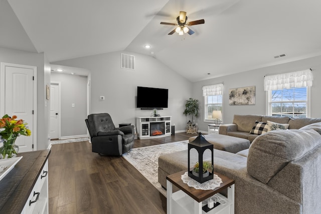 living room featuring a ceiling fan, visible vents, vaulted ceiling, and dark wood-style flooring