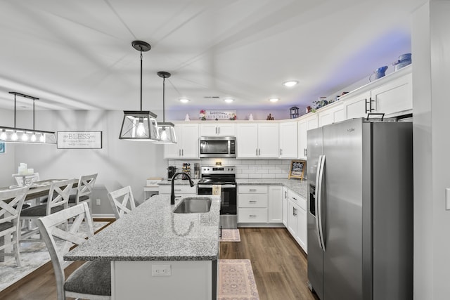 kitchen featuring a sink, white cabinetry, hanging light fixtures, appliances with stainless steel finishes, and backsplash