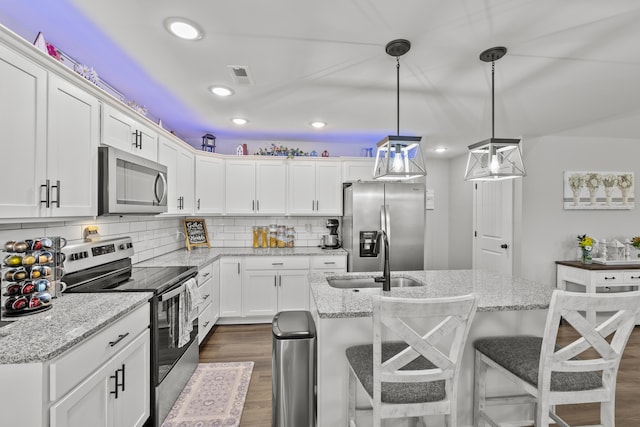 kitchen featuring decorative light fixtures, stainless steel appliances, white cabinetry, a sink, and light stone countertops