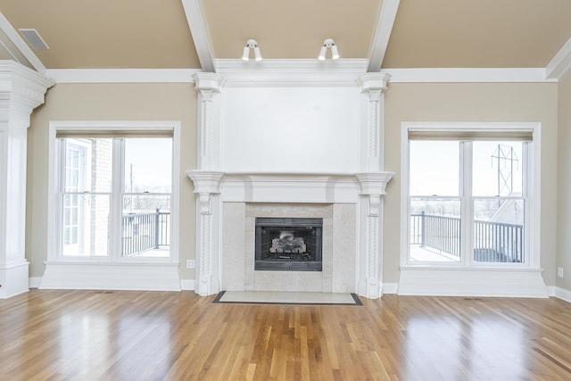 unfurnished living room with ornate columns, a wealth of natural light, and wood finished floors