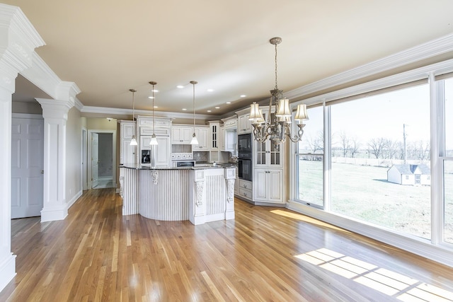 kitchen with an inviting chandelier, ornamental molding, light wood-style floors, black microwave, and glass insert cabinets
