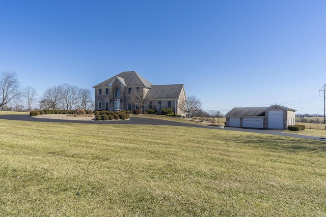 view of front of house with a front yard and a detached garage