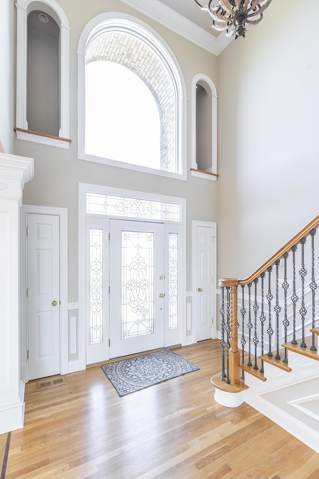 entryway featuring a high ceiling, ornamental molding, and wood finished floors