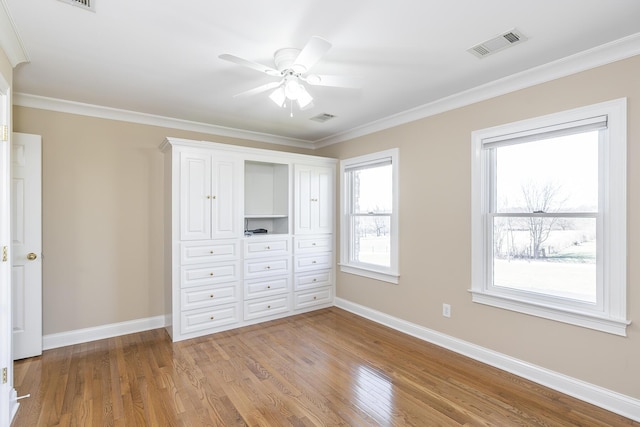 unfurnished bedroom with wood finished floors, ornamental molding, baseboards, and visible vents