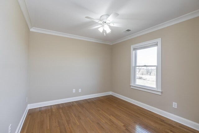 spare room featuring dark wood finished floors, baseboards, visible vents, and ornamental molding