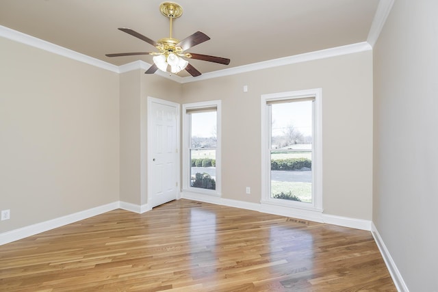 empty room with light wood finished floors, baseboards, visible vents, and crown molding