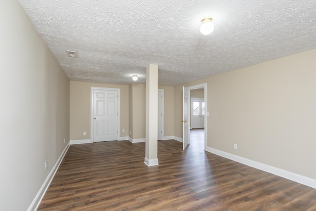 below grade area with dark wood-style floors, baseboards, and a textured ceiling