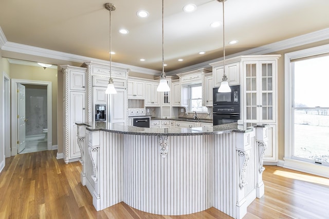 kitchen with a breakfast bar, glass insert cabinets, light wood-style flooring, black appliances, and ornamental molding