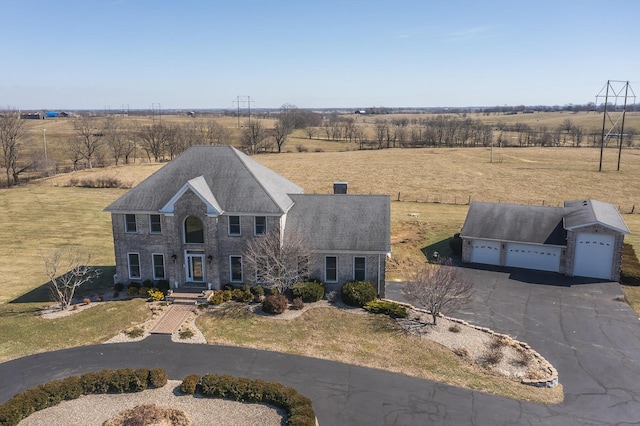 view of front of house with a rural view, aphalt driveway, a front lawn, a garage, and a chimney