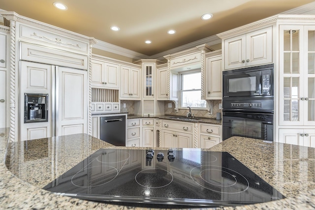 kitchen with a sink, stone counters, and black appliances