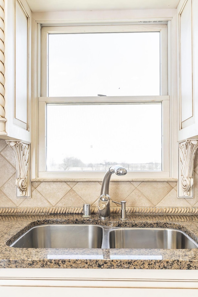 interior details featuring dark stone countertops, a sink, and backsplash