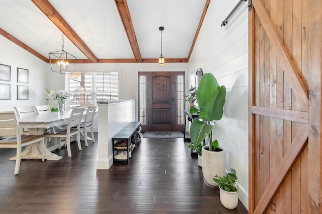 entrance foyer featuring dark wood-style flooring, lofted ceiling with beams, and an inviting chandelier