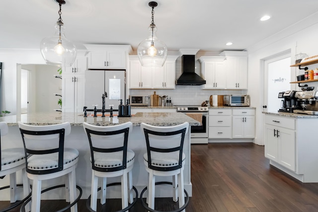 kitchen with stainless steel appliances, wall chimney range hood, white cabinetry, and pendant lighting