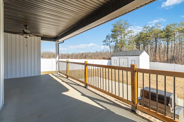 view of patio with a storage unit, an outdoor structure, a fenced backyard, and a ceiling fan