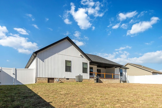 back of property with board and batten siding, crawl space, a yard, and a gate