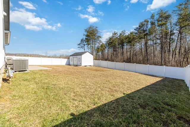 view of yard with an outbuilding, a fenced backyard, central AC unit, and a storage unit