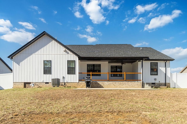 back of property with a shingled roof, crawl space, board and batten siding, and a lawn