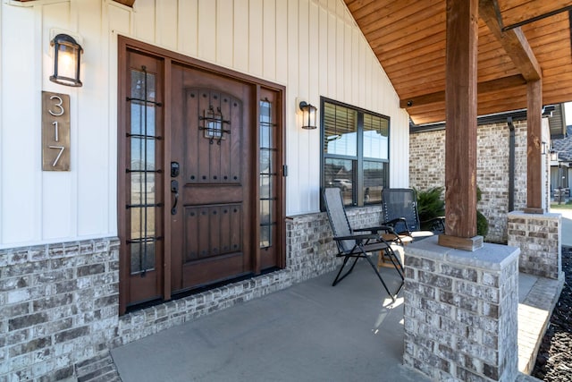 doorway to property featuring stone siding and covered porch