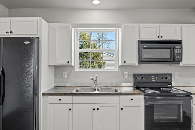 kitchen featuring dark countertops, recessed lighting, white cabinets, a sink, and black appliances