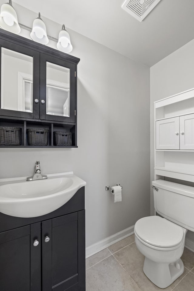 bathroom featuring baseboards, vanity, toilet, and tile patterned floors