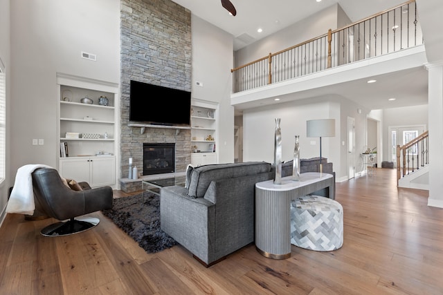 living room with built in features, visible vents, stairway, light wood-style floors, and a fireplace