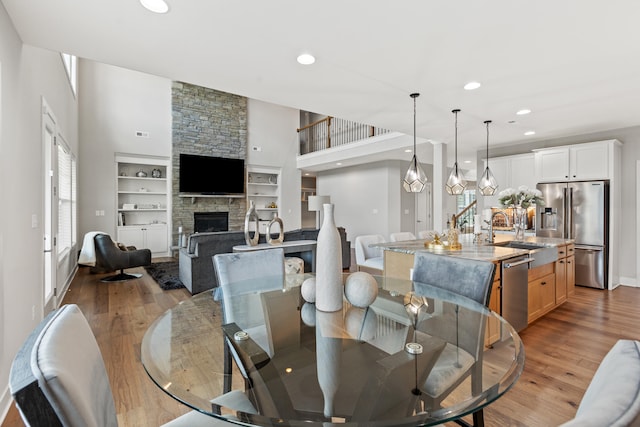 dining room with recessed lighting, a fireplace, light wood-style flooring, and stairs