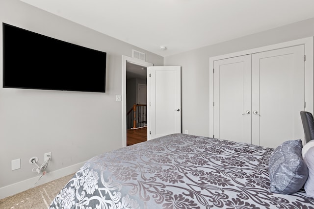 carpeted bedroom with a closet, visible vents, and baseboards