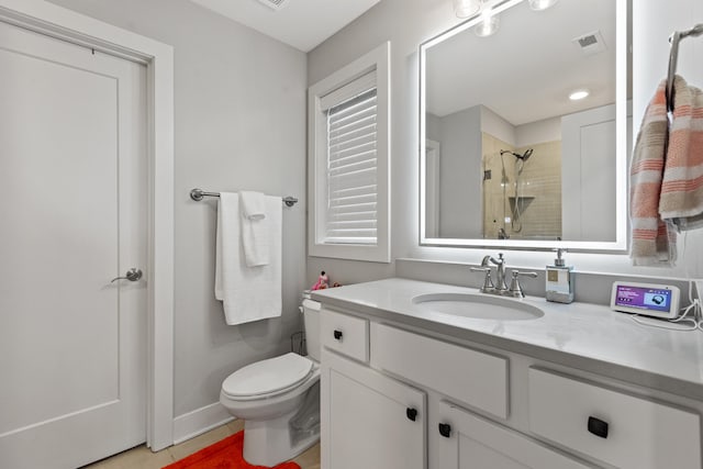 bathroom featuring toilet, vanity, a tile shower, and visible vents