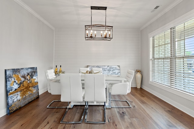 dining room featuring baseboards, visible vents, crown molding, and wood finished floors