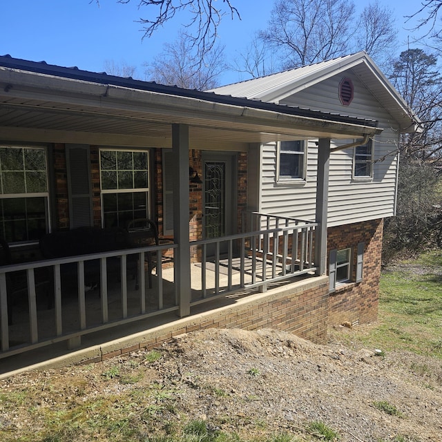 view of front of house featuring metal roof and brick siding