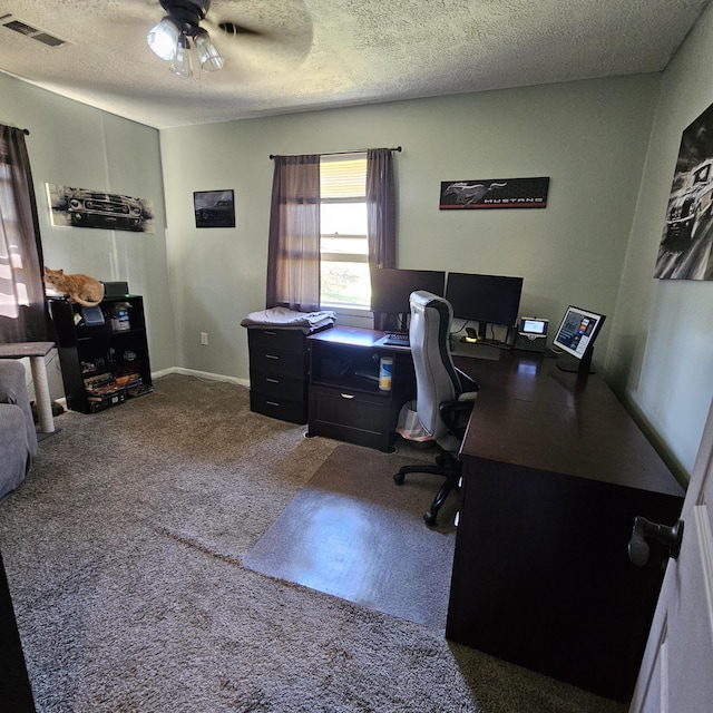 home office with a textured ceiling, carpet flooring, visible vents, and a ceiling fan