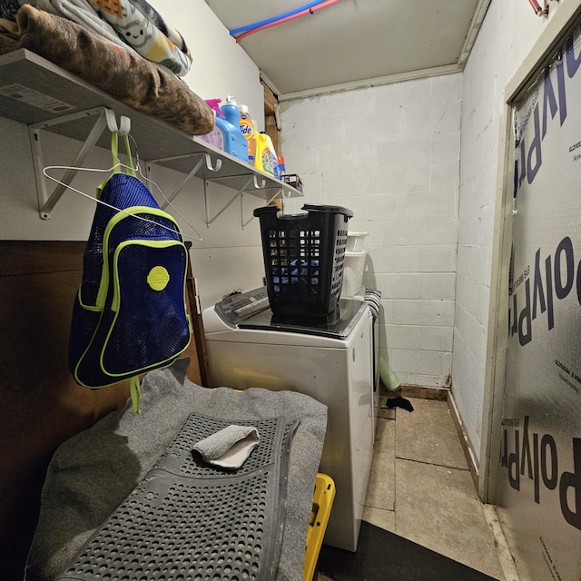 laundry area featuring concrete block wall and washing machine and clothes dryer