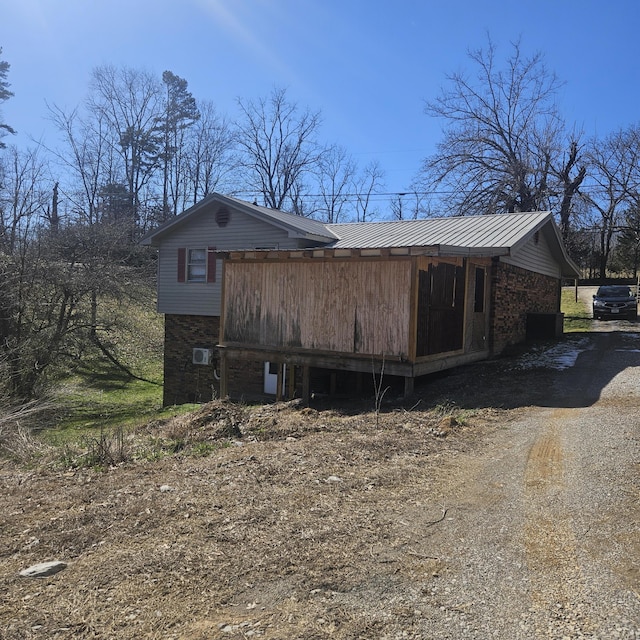 view of side of home featuring metal roof and driveway