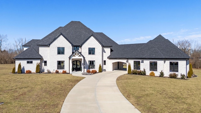 french provincial home with driveway, a front lawn, and roof with shingles