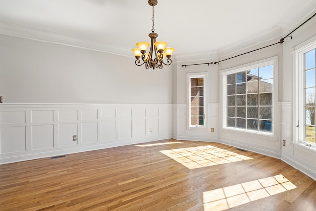 unfurnished room featuring a notable chandelier, crown molding, and light wood-style floors