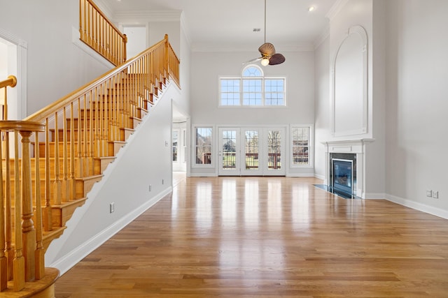 unfurnished living room featuring baseboards, wood finished floors, ornamental molding, and a fireplace with flush hearth