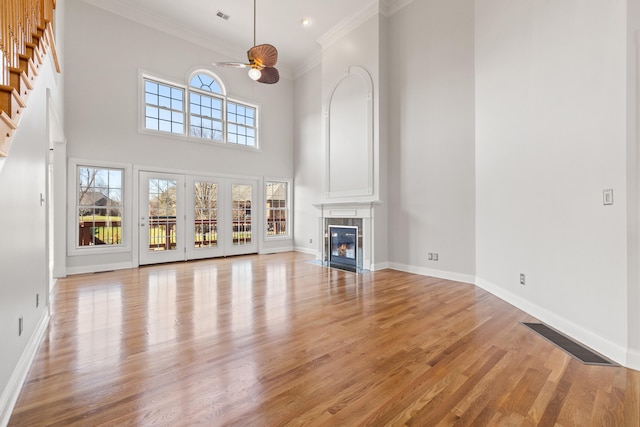 unfurnished living room featuring visible vents, baseboards, a premium fireplace, ornamental molding, and light wood-type flooring