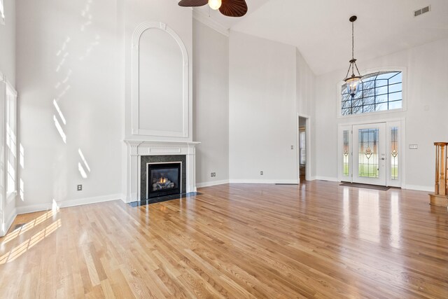 unfurnished living room featuring visible vents, a ceiling fan, a fireplace, and light wood finished floors