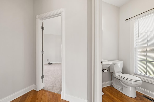 bathroom featuring toilet, wood finished floors, visible vents, and baseboards