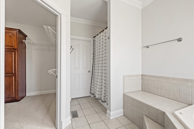 bathroom featuring a spacious closet, visible vents, tiled bath, ornamental molding, and tile patterned floors