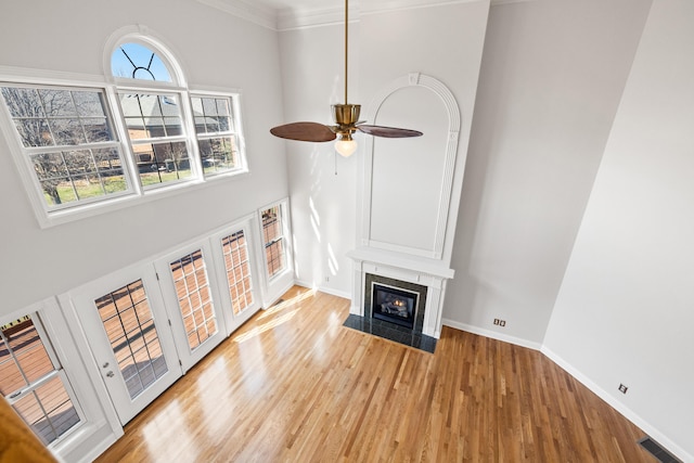 unfurnished living room featuring visible vents, baseboards, a fireplace with flush hearth, ceiling fan, and light wood-style floors