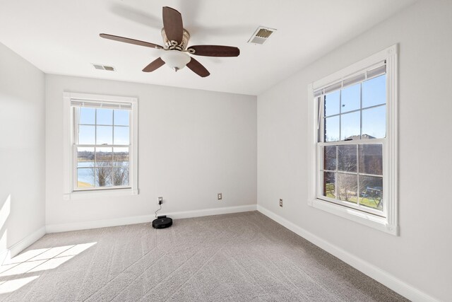 carpeted spare room featuring a ceiling fan, baseboards, and visible vents