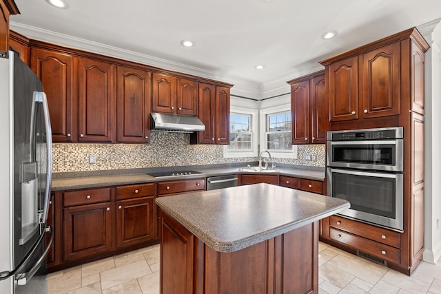 kitchen with a sink, decorative backsplash, under cabinet range hood, appliances with stainless steel finishes, and dark countertops