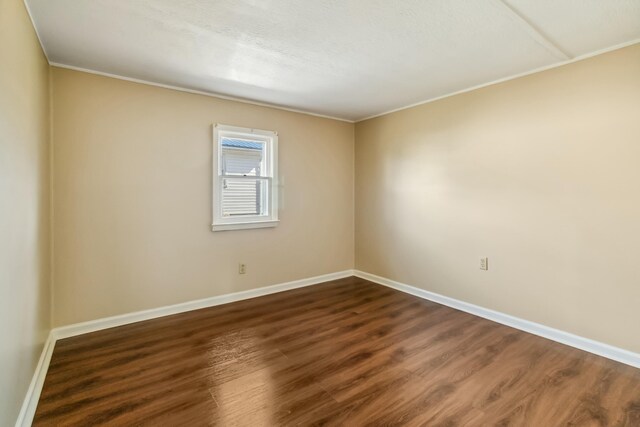 spare room featuring dark wood-style flooring and baseboards